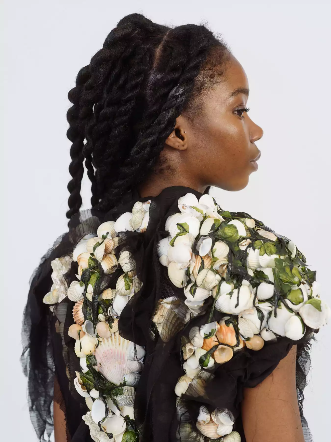 Cette photographie est le portrait de dos d’une mannequin portant une robe fleuri. Le mannequin tourne son profil vers la droite. La photographie est sur fond blanc, photographiée dans une studio photo. Le photographe est le photographe de mode Raul Guillermo. Né au Pérou il vit et travaille à Paris. Le photographe de mode Raul Guillermo est représenté par Alexis Antigny, le fondateur de l’agence d’artistes ANTIGNY AGENCY.