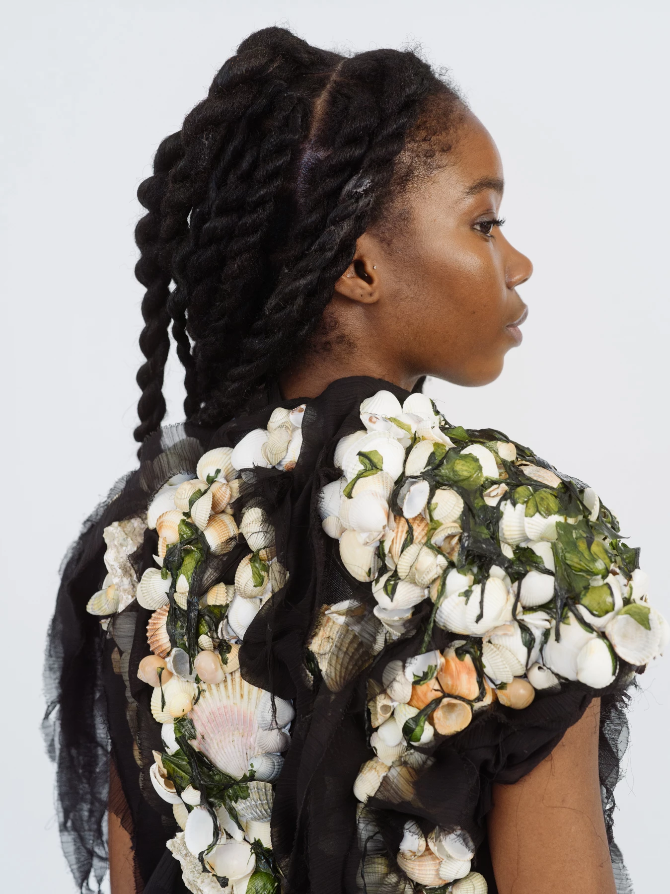 Cette photographie est le portrait de dos d’une mannequin portant une robe fleuri. Le mannequin tourne son profil vers la droite. La photographie est sur fond blanc, photographiée dans une studio photo. Le photographe est le photographe de mode Raul Guillermo. Né au Pérou il vit et travaille à Paris. Le photographe de mode Raul Guillermo est représenté par Alexis Antigny, le fondateur de l’agence d’artistes ANTIGNY AGENCY.