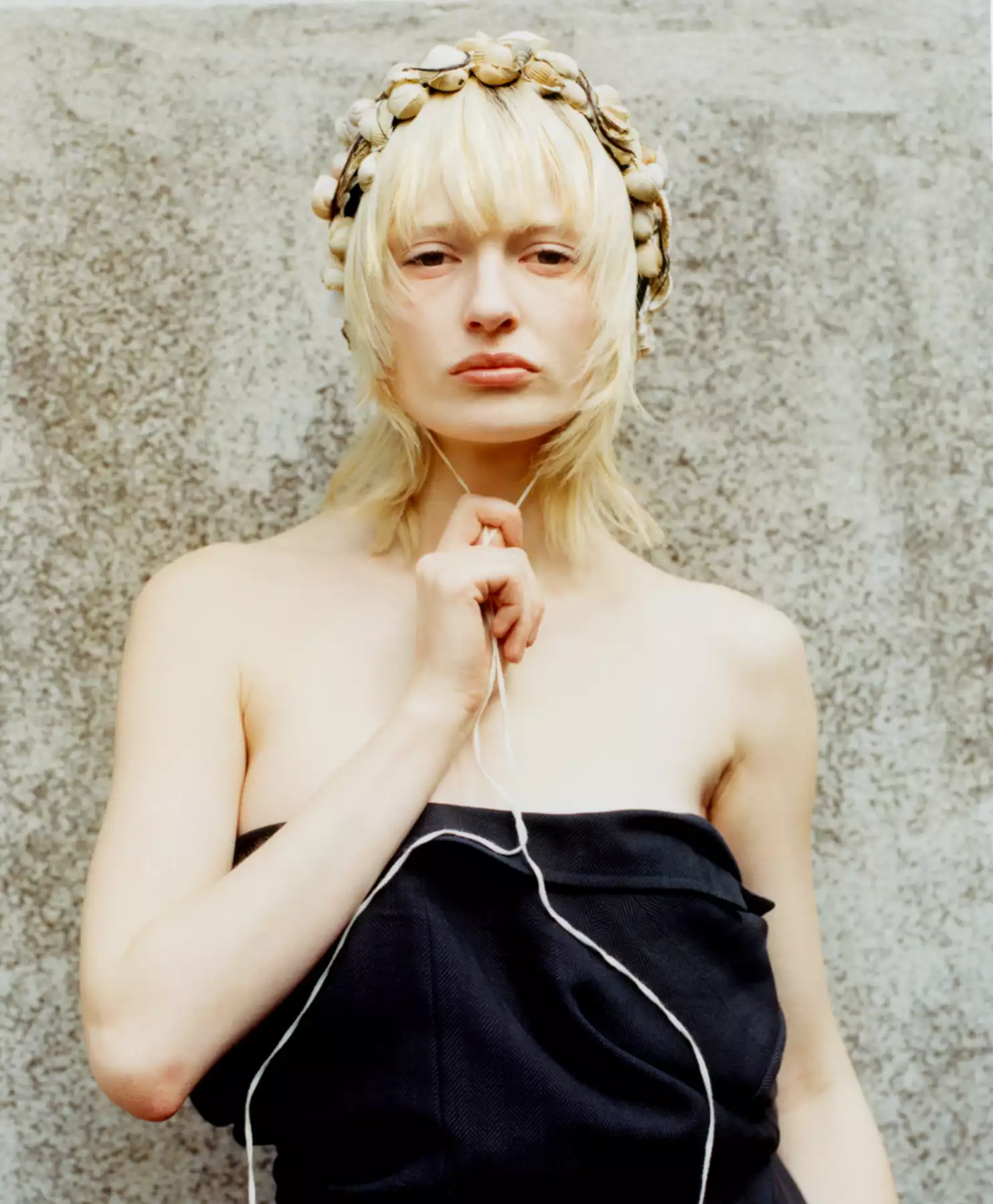 Le photographe Raul Guillermo a photographié ce portrait d’une mannequin blonde. La mannequin blonde est photographié sur un mur, en extérieur. La mannequin porte une robe noire et un serre-tête. Elle nous regarde d’un regard assuré. Le photographe Raul Guillermo est une photographe de mode qui photographie tant à l’argentique qu’au numérique. L’agent du photographe Raul Guillermo est Alexis Antigny, le créateur de l’agence ANTIGNY AGENCY