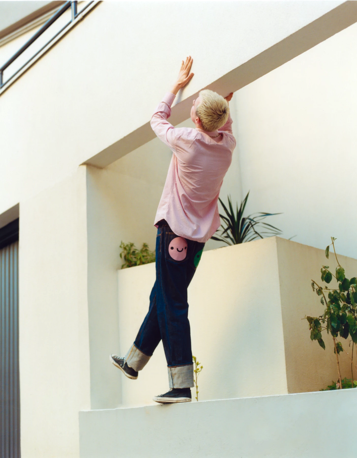 Cette photographie a été shootée par le photographe de mode Raul Guillermo. Ici le photographe d’origine péruvienne a photographié un mannequin de dos, portant une chemise rose qui essaye d’escalader une architecture blance très moderne. Cette photographie a été prise en extérieur par le photographe de mode Raul Guillermo.