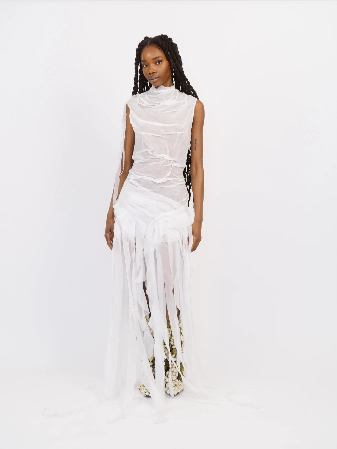 Cette photographie est une oeuvre du photographe de mode Raul Guillermo. La photographie ici présente représente le portrait en pied d’une mannequin. La mannequin est photographiée vétue d’une robe blanche sur un fond blanc, en studio. Raul Guillermo aime photographier se type de portrait de mode.